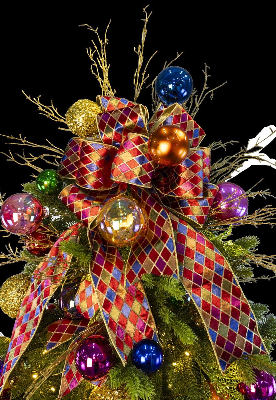 Close up of a harlequin ribbon bow over jewel-toned ornaments